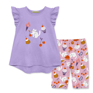 Children's outfit with purple top and pink bike shorts featuring cat and cupcakes  designs on a white background, front