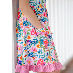 Colorful floral dress worn by a child with a white background.