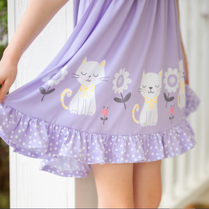 Lavender dress with cat and flower patterns held by a child.