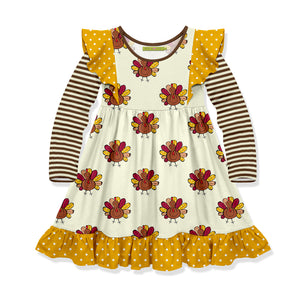 A cream colored dress with long sleeves featuring a turkey pattern and yellow dots on the border.