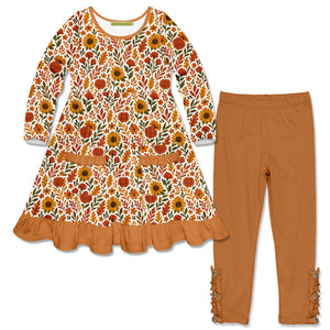 A girl's two-piece outfit set featuring a long-sleeve dress with a colorful sunflower and leaf pattern in orange, yellow, green, and white, paired with matching rust-brown leggings with ruffle details on the cuffs.