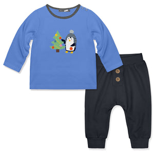 A baby boy's two-piece clothing set featuring a long-sleeve blue shirt with a penguin and Christmas tree graphic, paired with charcoal pants that have button details on the waist.