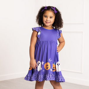 Young girl wearing a purple Halloween-themed dress with ghosts and pumpkins on a white background