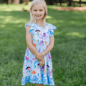 Young girls wearing a blue mermaid patterned dress standing outside in the grass, lifestyle, front - Millieloveslily.comt