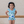 A young girl wearing a blue turtle patterned swimsuit with ruffles standing inside with her hands on her hips, lifestyle