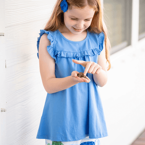 Girl standing on a porch holding a turtle wearing a blue  Top and Turtle Print Ruffle short, lifestyle