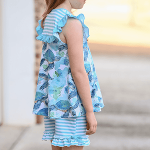 A young girl standing outside wearing a mint turtle ptinted top and matching stripe shorts, lifestyle