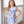 A young girl standing on a porch wearing a purple butterfly themed top and matching stripe short set, lifestyle