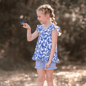 Young girl wearing a  Periwinkle Butterfly Printed Top and Solid Short holding a butterfly, lifestyle