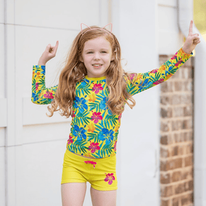 A young girl wearing  a yellow Neon Hawaiian print Long Sleeve Rashguard & swim short set standing in front of a white background, lifestyle UPF 50+, Millieloveslily.com