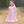 A young girl standing on a dirt path wearing a Pink rodeo themed Dress with a pink bow in her hair, lifestyle 