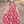 A young girl wearing a red floral hi-low mid-length dress standing outside is a forest like area, lifestyle
