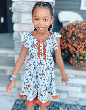 A young girl standing outside wearing a  Rodeo themed  Ruffle Front Angel - Sleeve Dress - Millieloveslily.com