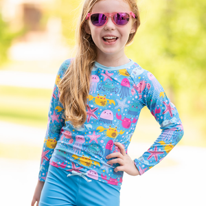 Young girls wearing a  Turquoise Octopus Sea themed Long Sleeve Rashguard and swim short Set, outside , lifestyle