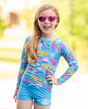 Young girls wearing a  Turquoise Octopus Sea themed Long Sleeve Rashguard and swim short Set, outside , lifestyle