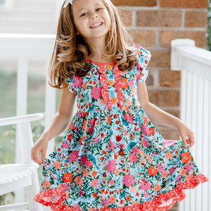 a young girl wearing a blue and orange  floral print Angel - Sleeve Dress standing outside, lifestyle- Millieloveslily.com