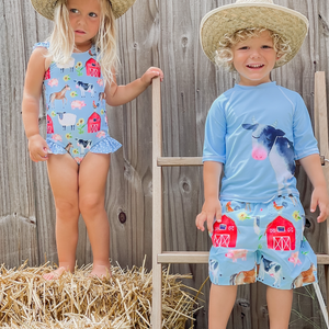 A young boy and girl wearing matching blue barn amimal themed swimsuits wearing strawhats, lifestyle, front- Millieloveslily.com