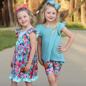 2 young girls wearing matching prints. One wearing a kitten & floral printed dress and the other wearing a kitten and floral printed bike short with matching cotton top standing outside Millieloveslily.com