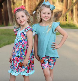 2 young girls wearing matching prints. One wearing a kitten & floral printed dress and the other wearing a kitten and floral printed bike short with matching cotton top standing outside Millieloveslily.com