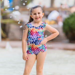 young girl wearing a multicolored Mermaid Scale patterned One - Piece  swimsuit- standing in a pool, lifestyle, front Millieloveslily.com