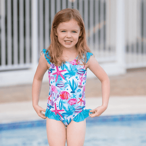 young girl wearing an ocean themed One - Piece swimsuit standing in a pool, lifestyle, front- Millieloveslily.com