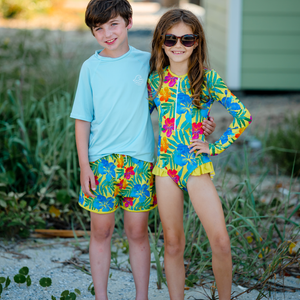 A young girl and boy wearing matching Yellow Hawaiian Neon swimsuits standing on the sand, lifestyle, front