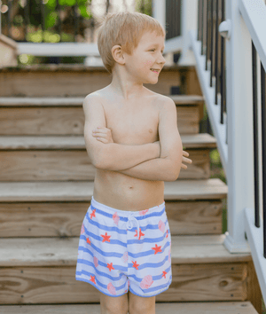 Boy wearing blue stripe swim trunks in front of steps outside, front