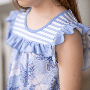 A closeup of a young girl  wearing a purple butterfly themed top and matching stripe short set, lifestyle