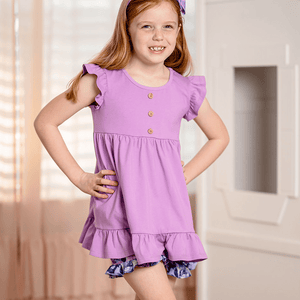 girls purple top and floral short set  with ruffled details in a softly lit room, front