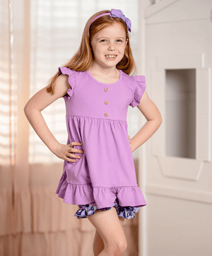 girls purple top and floral short set  with ruffled details in a softly lit room, front