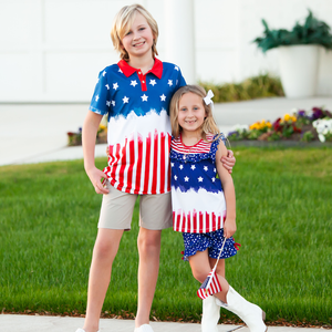A young girl and young boy standing outside wearing matching red, white & blue stars and stripe outfits with their arms around each other, lifestyle